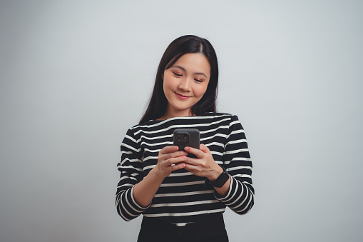 Asian woman using smartphone happy smiling standing isolated over white background.