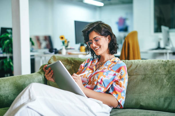 Businesswoman using digital tablet in office Cheerful businesswoman holding and swiping on digital tablet in office iranian ethnicity stock pictures, royalty-free photos & images