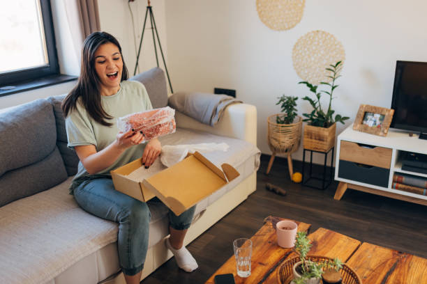 istock Cheerful woman opens a package that arrived at her home address, her face shows that she is satisfied with online shopping 1472104364
