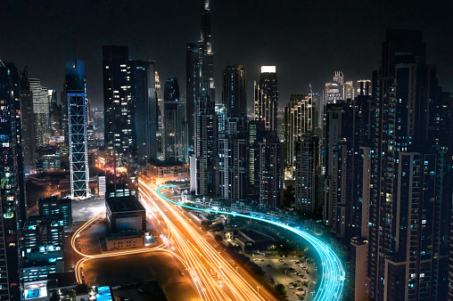 Skyline over city of Dubai, illuminated skyscrapers and trails of tail lights on busy streets at night