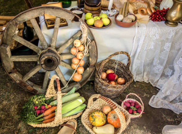 Rustic vintage autumn, fall background with ripe ribbed pumpkins on straw near wooden wheel of cart.  Rural-style decorations.