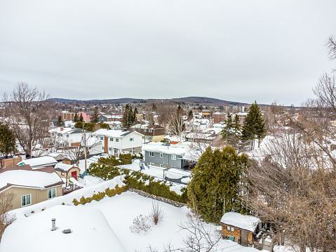 Suburban house with snow on the ground and more falling