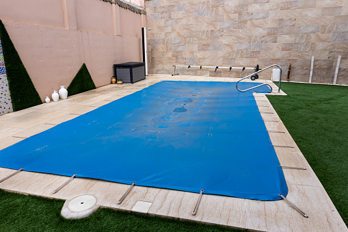 Pequeña piscina cubierta con una lona azul durante la temporada de invierno para cubrirla y evitar la suciedad. photo