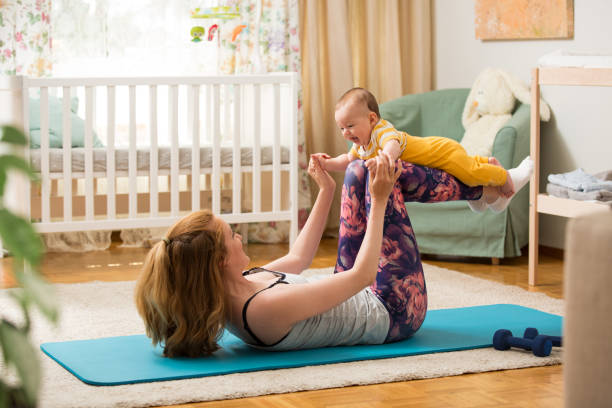 istock Young mother working out at home on a mat with baby 1472107815