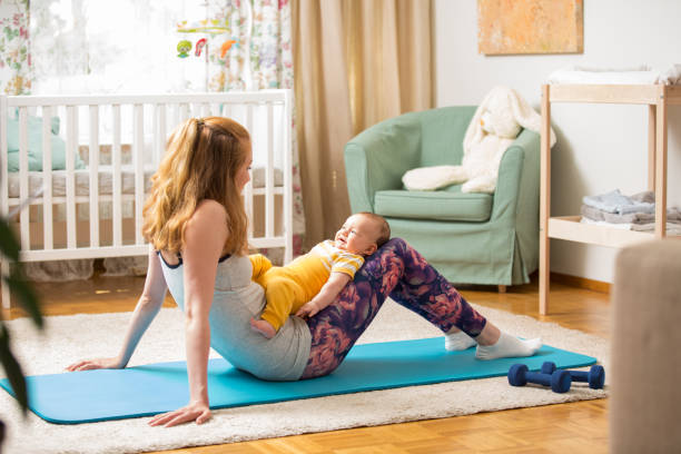 istock Young mother working out at home on a mat with baby 1472107826