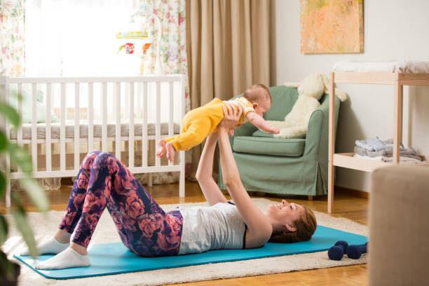 istock Young mother working out at home on a mat with baby 1472107951