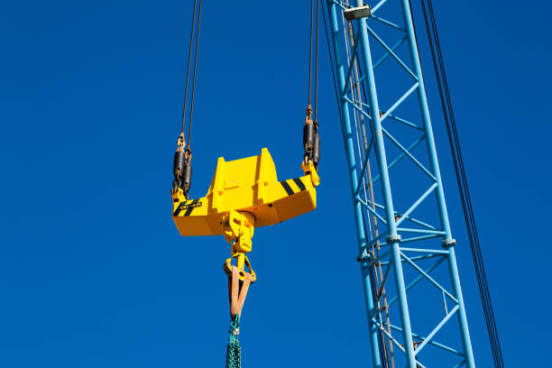 istock Crane boom with a stabilizer and a hook against a blue sky. 1472109517