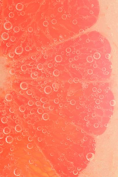 istock Slice of grapefruit in sparkling water. Grapefruit slice covered by bubbles in carbonated water. Grapefruit slice in water with bubbles 1472110816