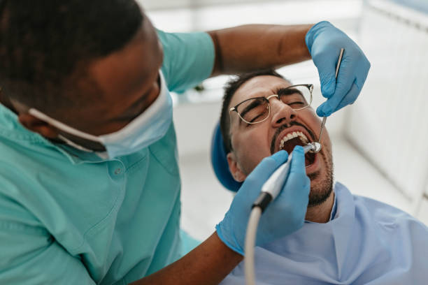 Feeling scared Man is sitting in the dentist's chair, with his mouth open while the dentist fixes his teeth dental drill stock pictures, royalty-free photos & images