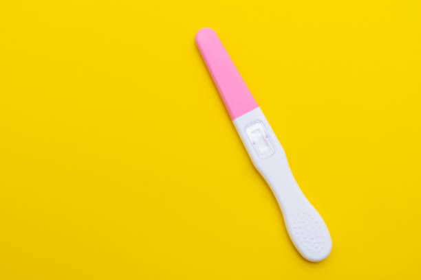 Side view of a woman holding a pregnancy test in her hand, representing a health and family planning moment.