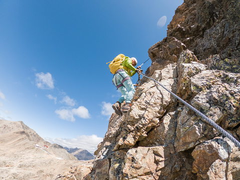 Wide angle view of sporty female climbing in summer on Via Ferrata in Switzerland.
Glacier in distance