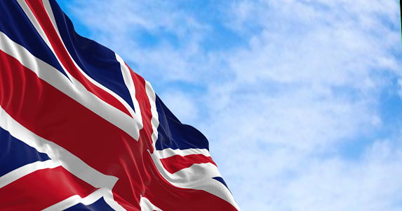 United Kingdom flag waving in the wind on a clear day. Union Jack. Blue field with red, white crosses of patron saints. Rippled fabric. 3d illustration render
