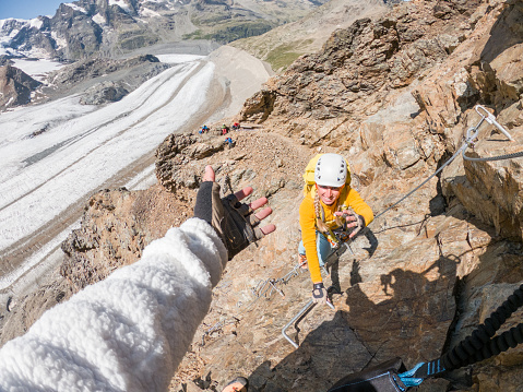 Young couple having fun climbing in Summer on via ferrata near glacier. Switzerland