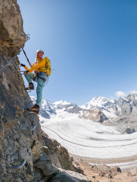 Female climber on via ferrata moving up the ladder, success and achievement concept, copy space stock photo