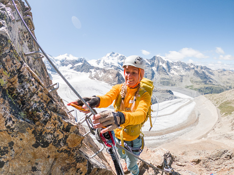 Young woman on Via Ferrata climbing up, glacier behind