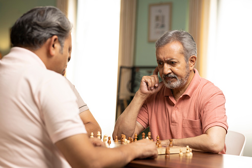 Senior man looking confused while playing chess
