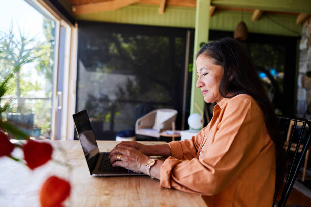 istock Smiling mature woman working from home using a laptop 1472115064