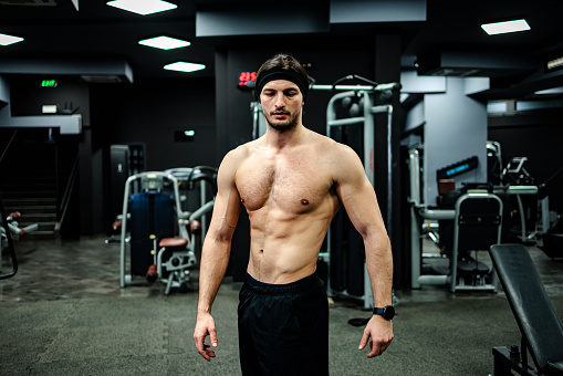 Strong young man posing in the gym