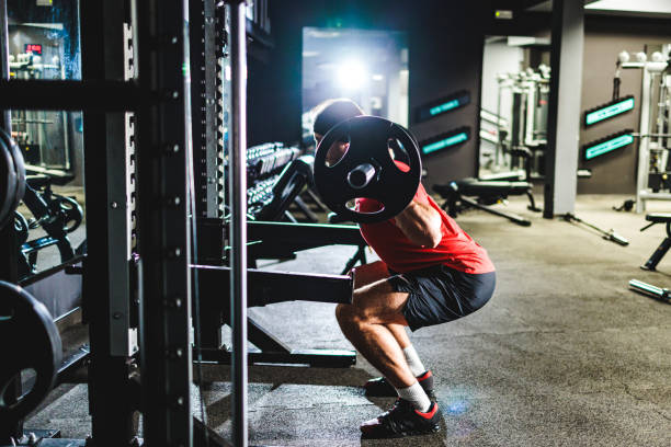 istock Man exercises squats in the gym 1472118439