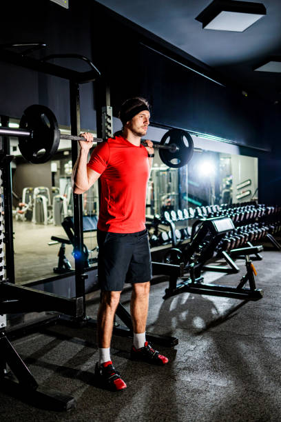istock Man exercises squats in the gym 1472118478