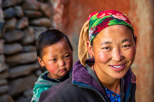 Young Tibetan woman carrying her baby in small village, Upper Mustang. Mustang region is the former Kingdom of Lo and now part of Nepal,  in the north-central part of that country, bordering the People's Republic of China on the Tibetan plateau between the Nepalese provinces of Dolpo and Manang.