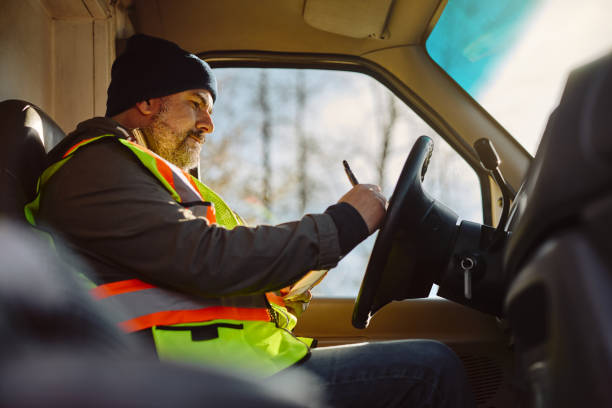 istock Truck driver writing on clipboard while sitting in vehicle cabin. 1472119008
