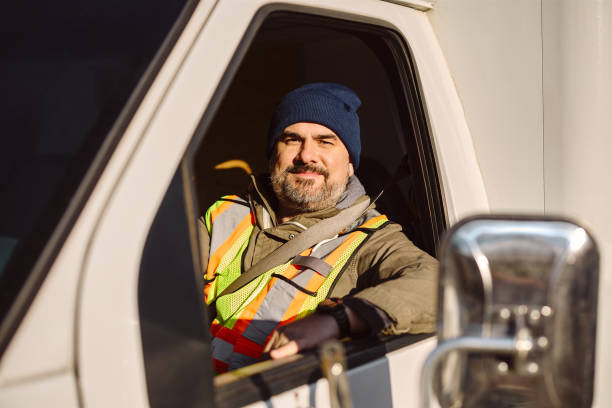 istock Smiling professional driver driving his truck and looking at camera. 1472119024