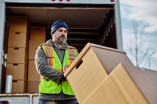 istock Delivery man loading packages for shipment into back of a truck. 1472119595