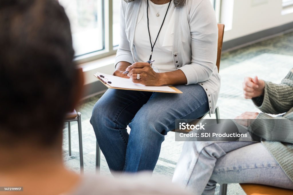 Unrecognizeable therapist takes notes during the meeting The unrecognizeable therapist takes notes during the meeting while listening to her clients talk. Mental Health Professional Stock Photo