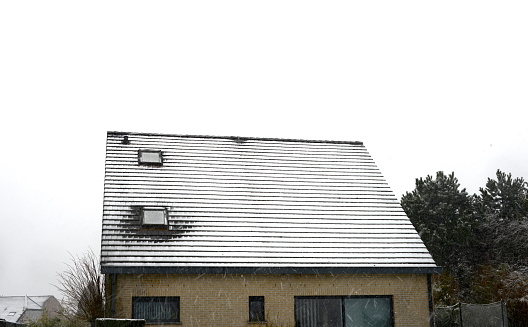 Leuven, Vlaams-Brabant, Belgium - March 8, 2023: this roof has the roof tiles around the skylight that are not covered with snow. This clearly indicates a loss of energy heating produced at a time when gas and fuel are very expensive in Europe