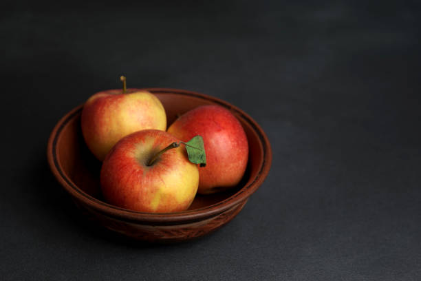 istock Three Red juicy Apples Lie in a clay Plate against a black background. Copy space 1472123257