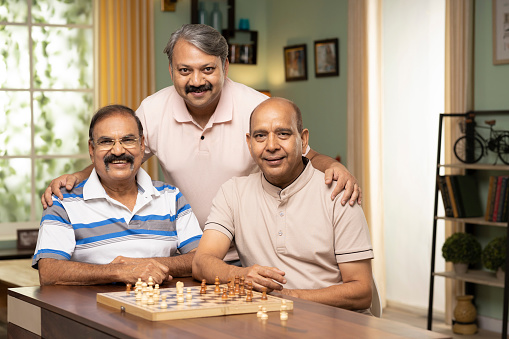 Portrait of three men with chess board in front of them