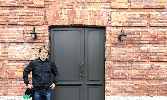 Young man standing near the front door of a brick house