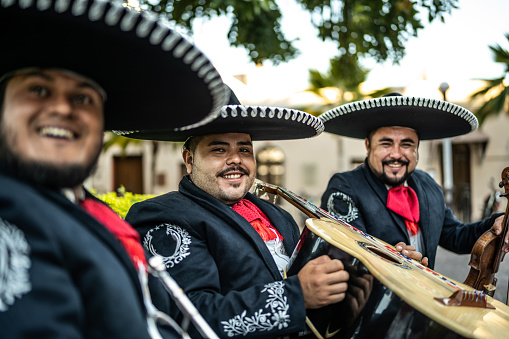 Portrait of young man traditional mariachi with friends sitting outdoors