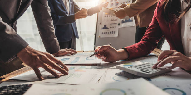 istock Business People Meeting using laptop computer,calculator,notebook,stock market chart paper for analysis Plans to improve quality next month. Conference Discussion Corporate Concept. 1472132206