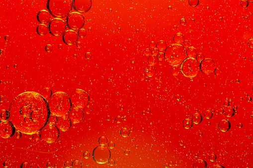 Macro red soft drink background,abstract background. drops of oil on water, red and green color. macro