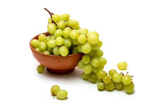 A bunch of ripe grapes in a plate on a white background