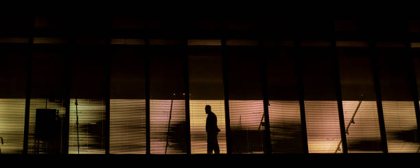 istock Silhouette of a man at the windows at night 1472141471