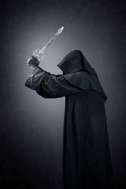 istock Dark knight with hooded cape and medieval sword over dark misty background 1472141792