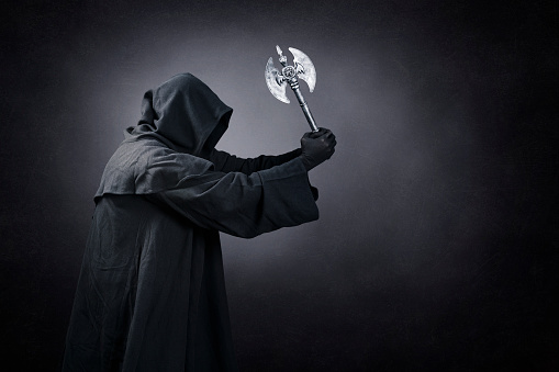 Figure in hooded cloak with axe over dark misty background