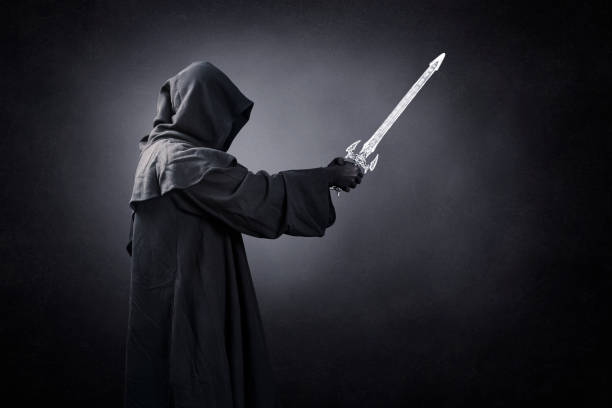 istock Dark knight with hooded cape and medieval sword over dark misty background 1472142467