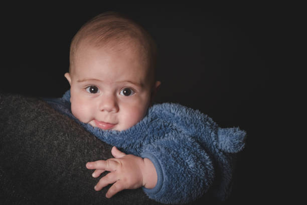 portret uroczego małego chłopca na ramieniu matki na czarnym tle - facial expression babies and children head and shoulders close up zdjęcia i obrazy z banku zdjęć