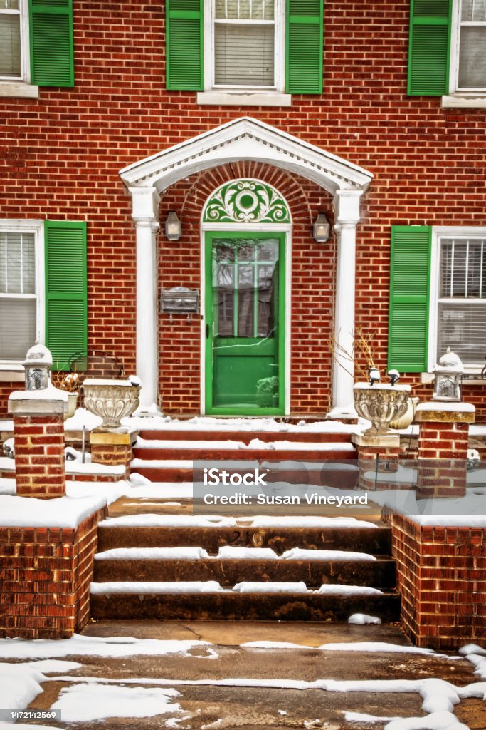 Brick house with bright green trim and shutters in snow -closeup of entrance with rock steps Antique Stock Photo