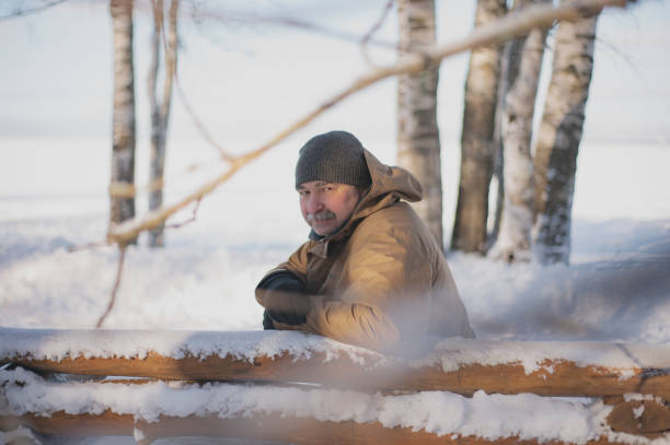 A man sits on a bench in a winter snowy park