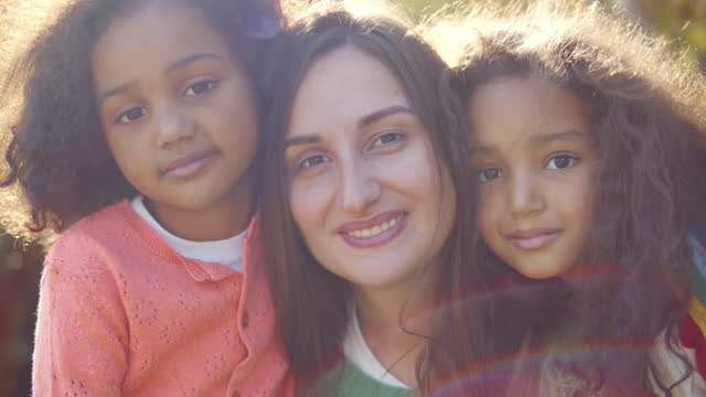 Caucasian mother and mixed-race children posing together. Realtime