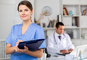 Positive nurse with folder of documents at office