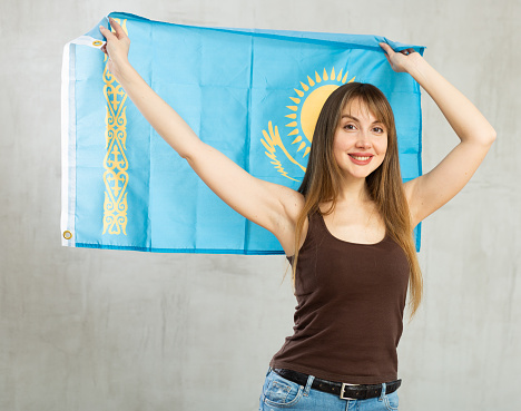 Cheerful young woman holding big Kazakhstan flag in her hands