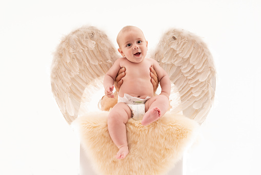 A baby wearing angel wings over white background