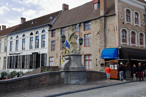 Bruges, Belgium - September 8, 2022: The statue of John of Nepomuk is an outdoor sculpture, installed on the side of the bridge over the canal in the old town of this medieval city