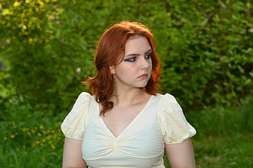 Portrait of a young redhead  girl in green nature, looking to the side